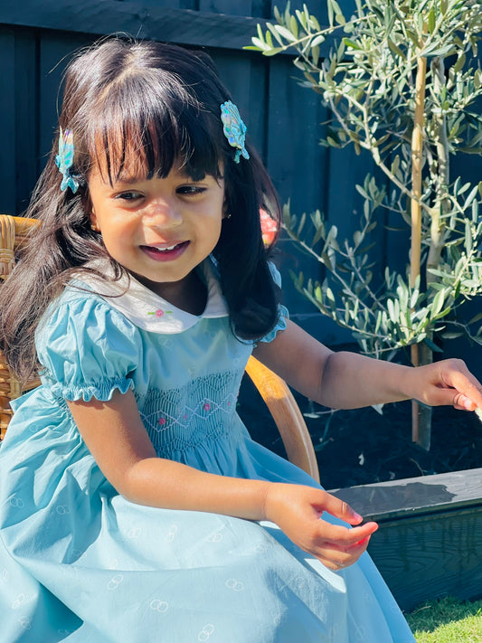 Bluebell hand-smocked dress in blue with white collar and pink rose bud embrodiery and blue white an dpink handsmocking