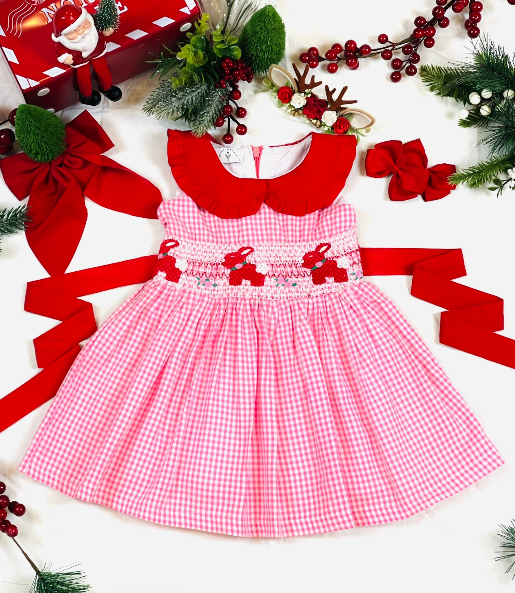 Red collar with frills, pink and white gingham dress with red hand-smocked bunnies and roses in the middle of the dress with a contrasting red rear bow stash.